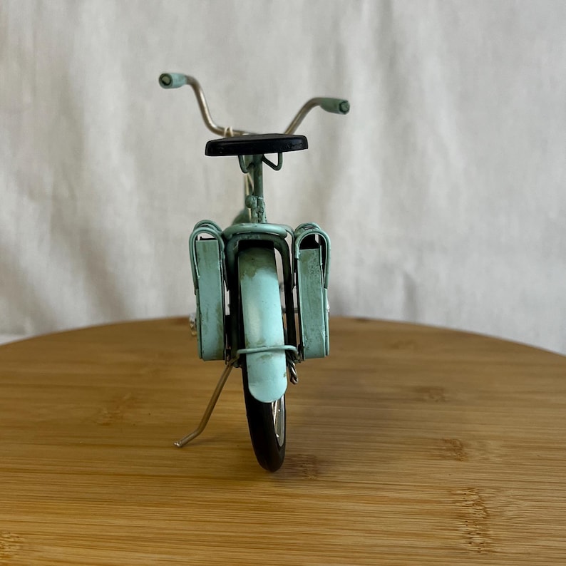 teal blue metal messenger bicycle with two metal messengers bags on the back and silver details