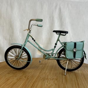 teal blue metal messenger bicycle with two metal messengers bags on the back and silver details