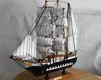 May include: A wooden model ship with white and black striped sails. The ship is on a wooden base with the word "BELÉM" written on it.