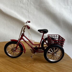 a red tricycle bike with a basket at the back