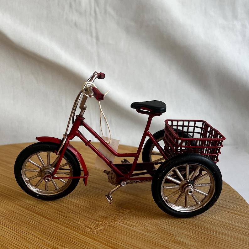 a red tricycle bike with a basket at the back
