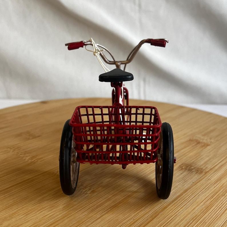 a red tricycle bike with a basket at the back
