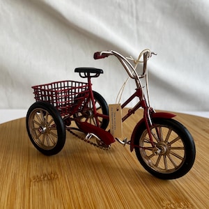 a red tricycle bike with a basket at the back