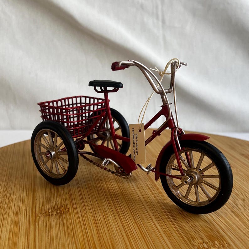 a red tricycle bike with a basket at the back
