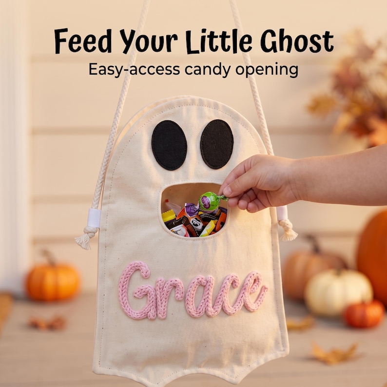 Puede incluir: Una bolsa de dulces de lona color crema con forma de fantasma, ojos de fieltro negro y una abertura central. El nombre Grace est&aacute; bordado en hilo rosa en el frente. La bolsa tiene un asa de cuerda blanca y el texto Feed Your Little Ghost.