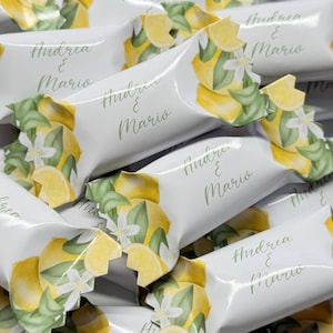 Puede incluir: Bolsas de regalo blancas con un diseño de limón y flores. Las bolsas están decoradas con el texto "Andrea & Mario".