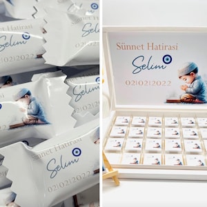 May include: White box with a lid, filled with individually wrapped chocolates. Each chocolate wrapper features a blue eye symbol, the name "Selim", and the date "02/10/2022". The box lid has the same design, with a watercolor illustration of a child.