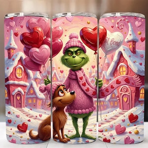 Puede incluir: Un vaso con una ilustración del Grinch y Max en un pueblo nevado. El Grinch lleva un suéter rosa y sostiene globos en forma de corazón. El fondo muestra casas rosas y corazones cayendo, con temática de San Valentín.