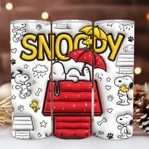 Puede incluir: Un vaso blanco con ilustraciones de Snoopy y Woodstock, y la palabra "SNOOPY" en amarillo. Snoopy se representa en su caseta roja, bajo un paraguas, y en otras poses. El vaso está decorado con corazones, huellas de patas y huesos.