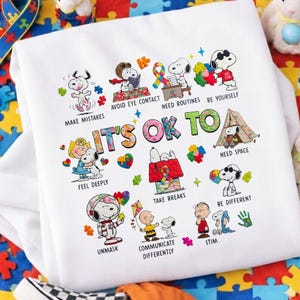 Puede incluir: Una taza de cerámica blanca con un asa negra y el texto "But First, Coffee" en un estilo manuscrito. La taza está sobre una superficie blanca. La taza mide aproximadamente 10 cm de alto.