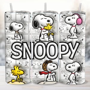 Puede incluir: Un vaso blanco con los personajes de Snoopy y Woodstock de la tira cómica Peanuts. El vaso tiene un fondo de cómic en blanco y negro con la palabra "SNOOPY" en letras blancas grandes.
