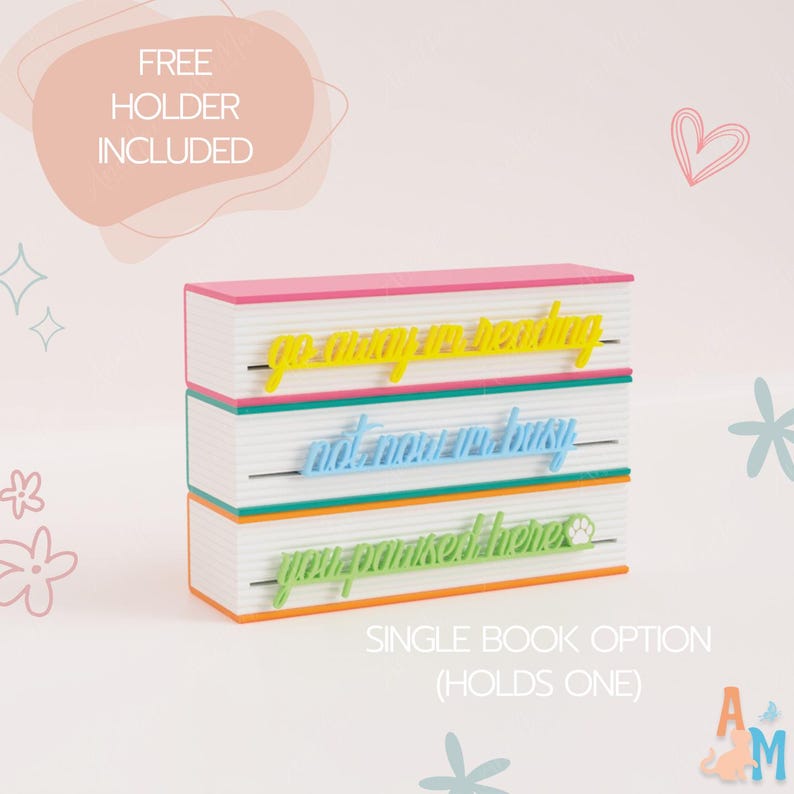 May include: A multi-layered book holder with three phrases: "go away to reading", "not now I'm busy", and "you promised here". The holder is white with pink, green, and orange accents. The text "FREE HOLDER INCLUDED" is also visible.