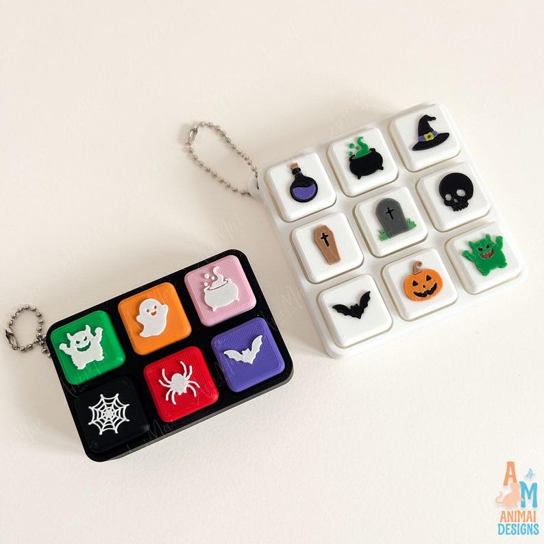 May include: Two rectangular keycap sets with Halloween-themed icons. The black set features a green monster, white ghost, pink cauldron, black spiderweb, red spider, and purple bat. The white set includes a potion, cauldron, hat, coffin, tombstone, skull, bat, pumpkin, and green monster.