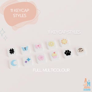 Op de afbeelding: Een collectie van 11 witte vierkante toetsenbordtoetsen met diverse kleurrijke iconen, waaronder een hashtag, vlinder, strik, bloem, zon, maan, sterretjes, cupcake, pootafdruk en een gezichtje. De tekst 11 KEYCAP STYLES is duidelijk zichtbaar.