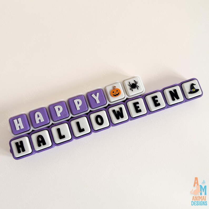 May include: A set of square, purple-bordered tiles arranged in two rows spelling HAPPY HALLOWEEN. The tiles feature white letters, a small orange jack-o'-lantern, a black spider, and a black witch hat icon on a white background.