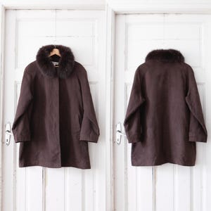 Könnte beinhalten: Ein brauner Wildledermantel mit einem Kunstfellkragen. Der Mantel hat einen Knopfverschluss und lange Ärmel.