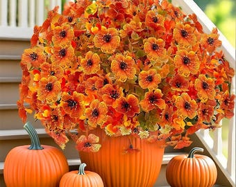 Puede incluir: Una composición otoñal con flores naranjas en una maceta con forma de calabaza, con tres calabazas. Las calabazas y la maceta son naranjas, las flores tienen centros oscuros. El conjunto está sobre escalones.