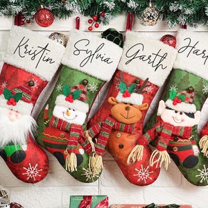 Könnte beinhalten: Fünf personalisierte Weihnachtsstrümpfe mit den Namen Kristin, Sylvia, Garth, Harley und Betty. Jeder Strumpf zeigt einen anderen festlichen Charakter: Weihnachtsmann, Schneemann, Rentier, Elf und Pinguin. Rote und grüne Farben.