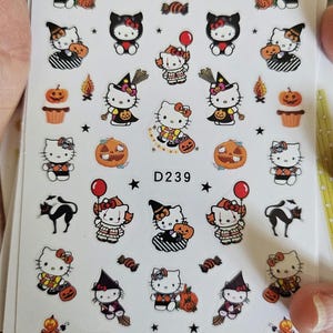 May include: Sheet of Halloween-themed stickers featuring Hello Kitty characters in various costumes, pumpkins, and the text "National Pumpkin Day." Includes black cats, candy, and stars. The sticker sheet has the number "D239" printed on it.