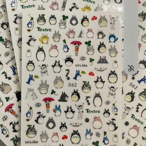 May include: A sheet of stickers featuring Totoro, a popular character from the Studio Ghibli film My Neighbor Totoro. The stickers are colorful and feature various images of Totoro, including Totoro with a mushroom, Totoro with a clover, and Totoro with a black soot sprite. The stickers are perfect for adding a touch of whimsy to your belongings.