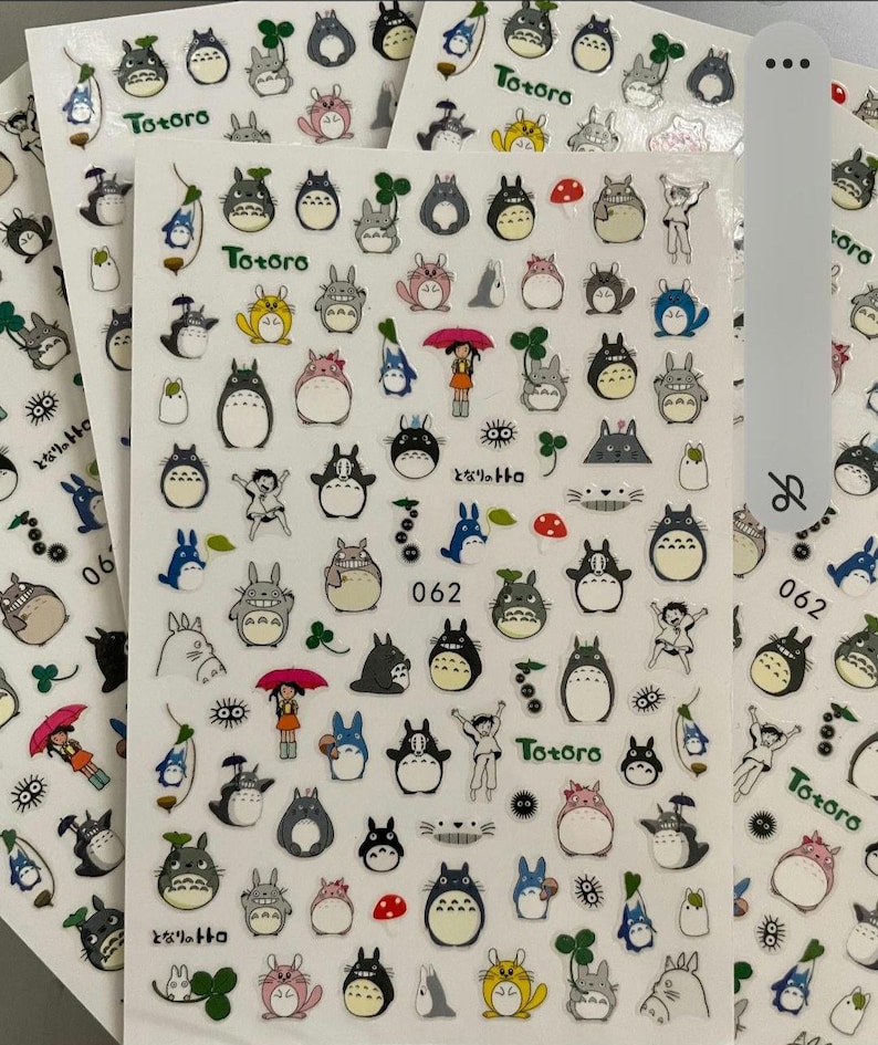 May include: A sheet of stickers featuring Totoro, a popular character from the Studio Ghibli film My Neighbor Totoro. The stickers are colorful and feature various images of Totoro, including Totoro with a mushroom, Totoro with a clover, and Totoro with a black soot sprite. The stickers are perfect for adding a touch of whimsy to your belongings.