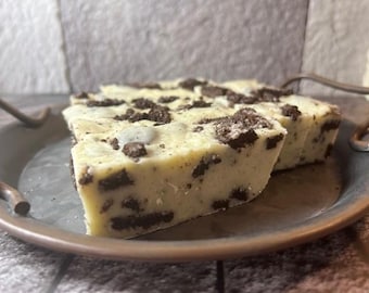 May include: A close-up of a white chocolate fudge with crushed Oreo cookies. The fudge is on a metal tray.