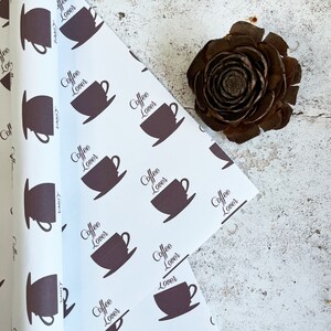 Puede incluir: Papel de regalo blanco con un patrón repetido de tazas de café marrones y el texto "Coffee Lover".