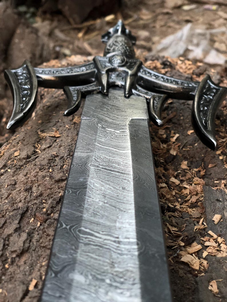 May include: A close-up of a sword with an intricate, ornate handle and a blade with a distinctive, wavy pattern.