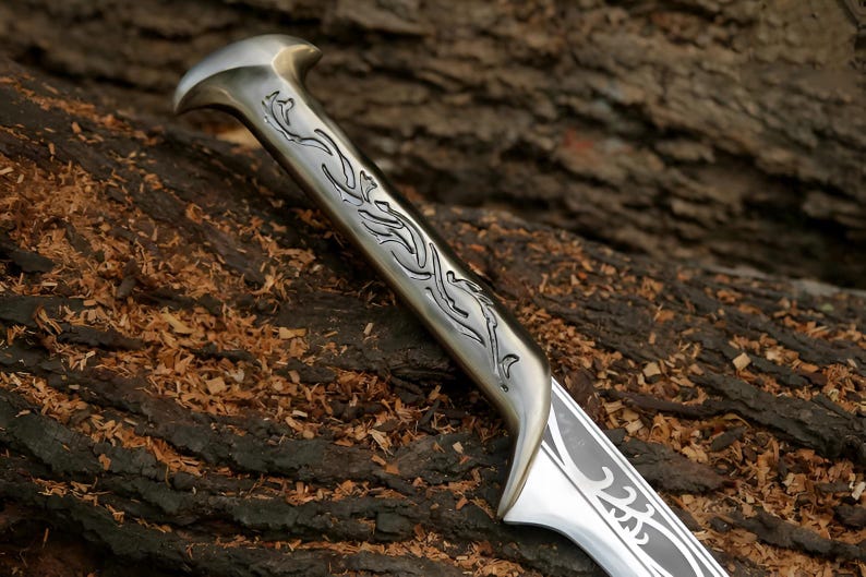May include: A silver sword with a detailed, intricate design on the handle and blade. The handle is decorated with a floral pattern.
