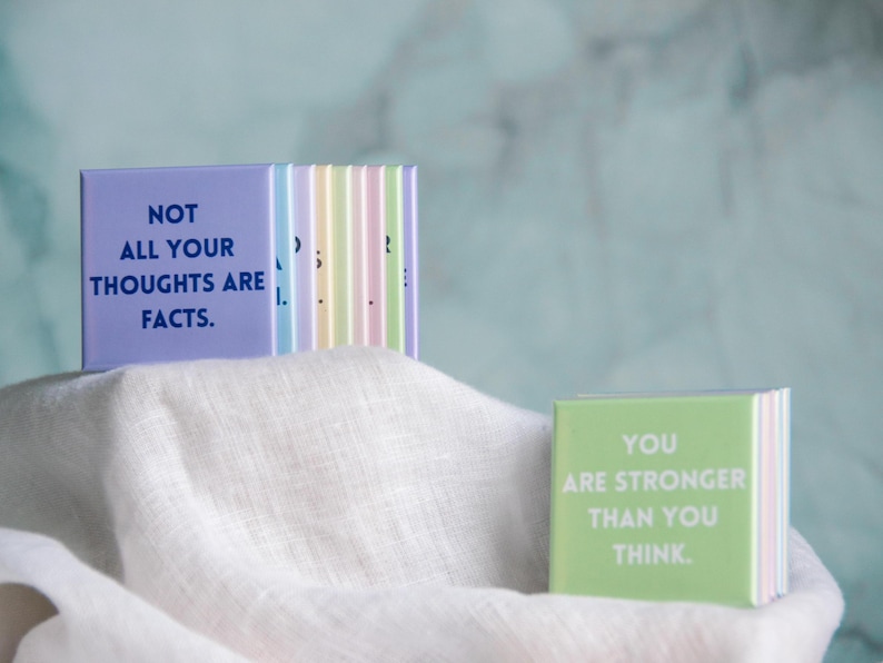 May include: A set of square magnets in pastel colors featuring motivational text. One lavender magnet displays the dark blue text NOT ALL YOUR THOUGHTS ARE FACTS. A light green magnet shows the white text YOU ARE STRONGER THAN YOU THINK.