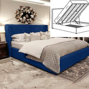 May include: A blue upholstered bed frame with a tufted headboard and a storage compartment underneath. The bed is made up with white and grey bedding and pillows. The bed frame has a lift-up mechanism for easy access to the storage space.