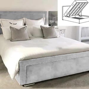 May include: A grey upholstered bed frame with a tufted headboard and a storage compartment underneath. The bed is made with white bedding and pillows.