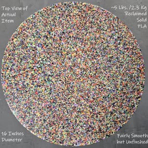 May include: A circular, reclaimed solid PLA item with a diameter of 16 inches. The item weighs approximately 5 lbs. The surface is fairly smooth but unfinished, and it is composed of a colorful, speckled pattern.