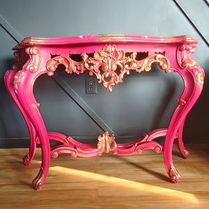 May include: A white ceramic mug with a black handle and the text "But First, Coffee" in a black, handwritten-style font. The mug is on a white surface.