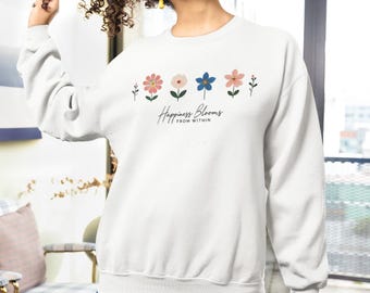 May include: White sweatshirt with a floral design and the text "Happiness Blooms From Within".