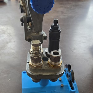 May include: A blue reloading press with a blue dial numbered 1 to 9. The press is mounted on a blue base with the text "Dillon Precision" printed on it.