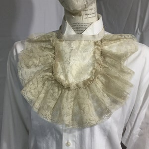 May include: A white lace collar with a ruffled edge. The collar is made of delicate lace and has a vintage look.
