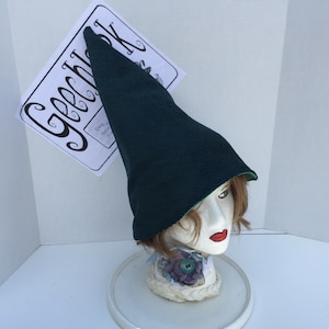 May include: A dark green pointed hat with a green lining. The hat is on a mannequin head with brown hair.