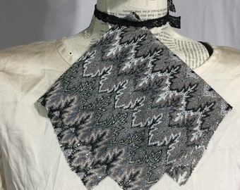 May include: A black and white patterned fabric scarf with a geometric design. The scarf is made of a soft, lightweight material and is perfect for adding a touch of style to any outfit.