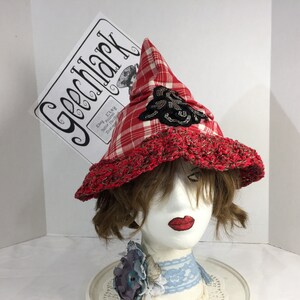 May include: Red and white plaid witch hat with a black crocheted brim and a black and silver embellishment. The hat is on a mannequin head.