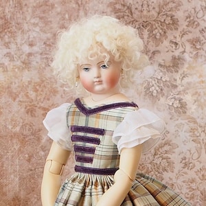 May include: A porcelain doll with blonde curly hair wearing a plaid dress with purple velvet trim and white lace sleeves.