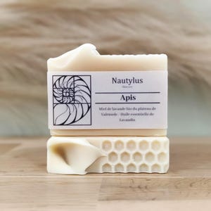 Puede incluir: Una barra de jabón blanca con una etiqueta que dice "Nautylus Skincare Apis Miel de lavande bio du plateau de Valensole - Huile essentielle de Lavandin"