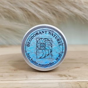 Peut inclure: Une boîte en étain argentée avec une étiquette bleue et blanche qui indique "Déodorant Naturel Aux huiles essentielles - 30 ml". L'étiquette présente un motif de coquille de nautile stylisé.