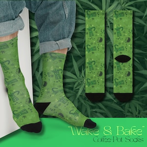 May include: Green socks featuring a repeating pattern of coffee pots, cannabis leaves, and the words "POT TEA." The socks have black heels and toes. The text "Wake & Bake" and "Coffee-Pot Socks" is at the bottom.