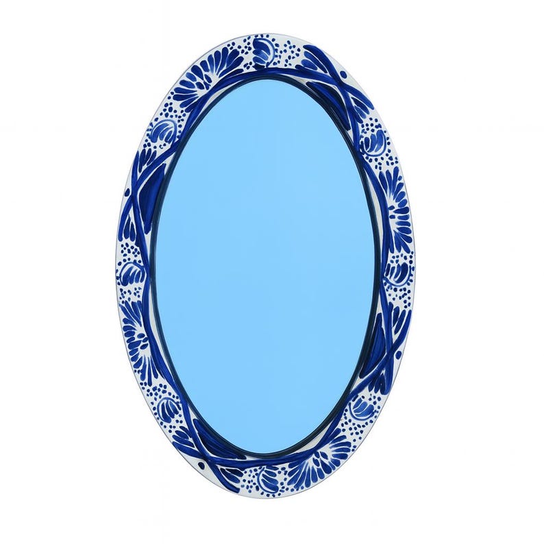 May include: Oval mirror with a light blue center and a decorative border. The border features a white base with blue floral and leaf patterns. The mirror's frame is a dark blue color.