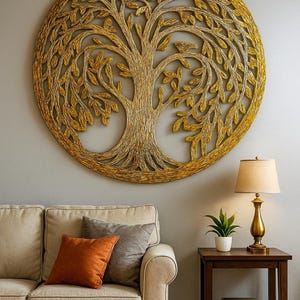 May include: A large, circular wall art piece depicting a tree of life design. The artwork is crafted from a golden-colored material, possibly rope or woven fibers, and is mounted on a gray wall. A beige sofa with orange and gray pillows sits below the artwork.