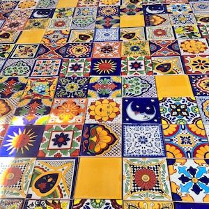 May include: A collection of colorful Mexican Talavera tiles with various designs, including flowers, suns, and moons. The tiles are arranged in a patchwork pattern.