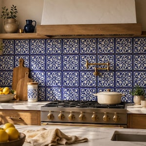 May include: A kitchen with a blue and white tile backsplash, wooden cabinets, and a stainless steel gas range. A wooden cutting board and a bowl of lemons are on the countertop. A beige pot sits on the stove.