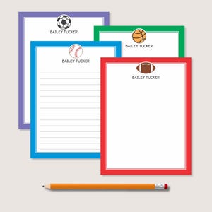 May include: Four rectangular notepads with colored borders in purple, green, blue, and red. Each notepad features a sports ball icon at the top, including a soccer ball, basketball, baseball, and football, with the printed name BAILEY TUCKER.
