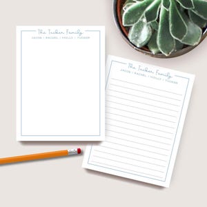 May include: Two white notepads with a light blue border and text that reads "The Tucker Family" and the names "Jacob, Rachel, Molly, Tucker". One notepad is lined. An orange pencil with a red eraser is on the left.